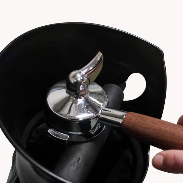 Coffee grinder with a wooden handle and metal top, held by a hand against a white background.